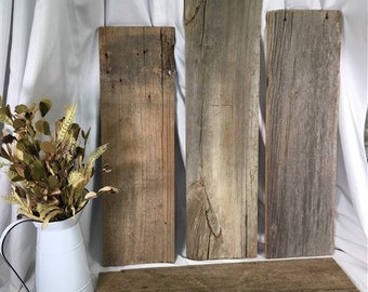 May include: Four rustic wooden planks with a natural wood grain and a weathered gray finish. The planks are arranged in a vertical stack with a smaller plank at the bottom.
