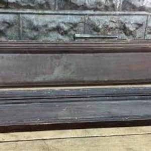 Può includere: Due elementi architettonici in legno marrone scuro e usurato. Il pezzo superiore è rettangolare con una maniglia, e il pezzo inferiore ha un bordo decorativo. Entrambi i pezzi mostrano segni di età e usura, suggerendo che siano recuperati o antichi.