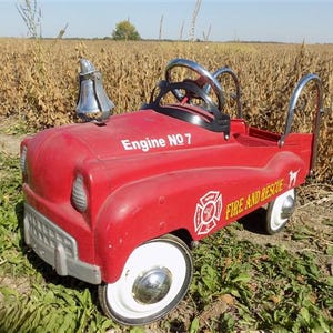 May include: Red toy fire truck with a bell on top, white wheels, and "Engine No 7" and "Fire and Rescue" printed on the side.