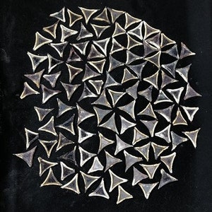 May include: A close-up of a black background with a circular arrangement of many small, clear, triangular glass pieces.
