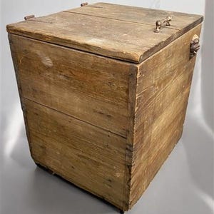 May include: A rustic wooden storage chest with a hinged lid. The chest is constructed from weathered planks, showcasing natural wood grain and knots. Metal hardware, including hinges and handles, adds to the vintage aesthetic. The chest is a warm, natural brown color.