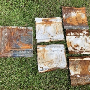 May include: Six antique tin ceiling tiles with a white and blue floral design. The tiles are showing signs of rust and wear.
