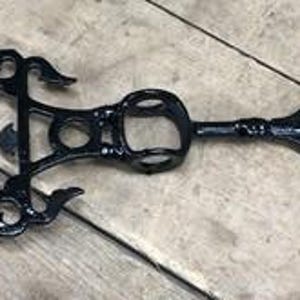 May include: Black metal weather vane arrow with ornate scrollwork and a decorative frame. The arrow features a pointed tip and a detailed design, suitable for outdoor decor.