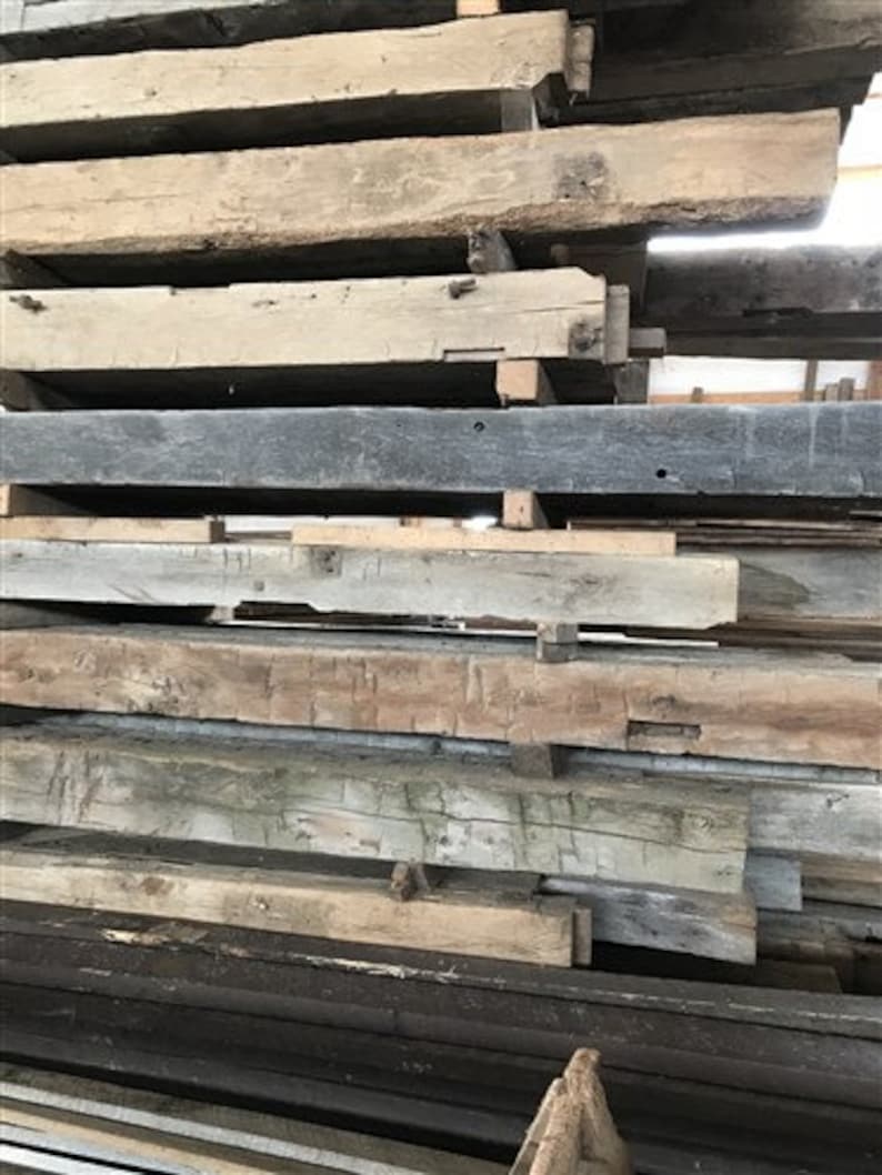 Puede incluir: Una pila de vigas de madera recuperada, algunas son de color marr&oacute;n oscuro, otras son de color marr&oacute;n claro y algunas son grises. Las vigas est&aacute;n apiladas en un orden aleatorio.