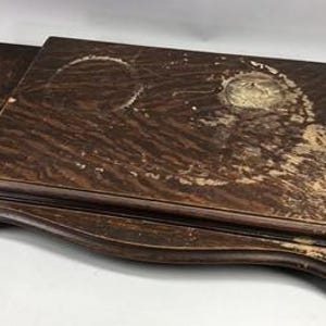May include: A rectangular dark brown wooden tray with a layered design and rounded edges. The surface features visible wear, including light-colored circular marks and scuffs across the wood grain, showing a distressed finish throughout.