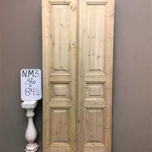 May include: A pair of solid wood double doors with raised panels. The doors are unfinished and have a natural wood color. The doors are 36 inches wide and 84 1/2 inches tall.