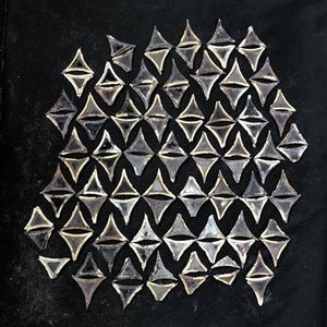 May include: A black background with a pattern of silver, diamond-shaped, reflective tiles.