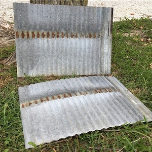 May include: Two sheets of corrugated metal roofing, each with a row of rusty nails along the top edge. The metal is weathered and has a gray patina.