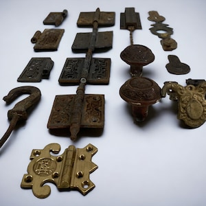 Peut inclure: Une collection de quincaillerie de porte antique, comprenant des charnières, des boutons et un crochet. La quincaillerie est en laiton et en fer et présente une variété de motifs ornés.