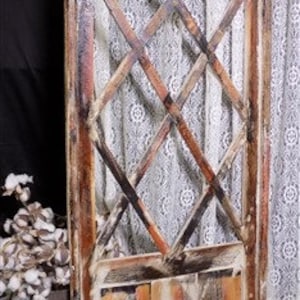 May include: A weathered wooden arched window with a diamond-shaped lattice design. The window is painted in shades of brown, white, and orange. The window is approximately 78 inches tall and 36 inches wide.