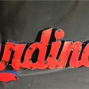 May include: Red metal sign with the word "Cardinals" in blue outlined letters. The sign has a distressed look with visible rivets.