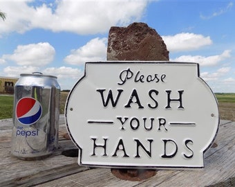 May include: White metal sign with black lettering that reads "Please Wash Your Hands". The sign is slightly curved and has a decorative border.
