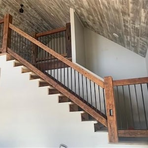 May include: A wooden staircase with black metal railings. The stairs are made of reclaimed wood and have a rustic look. The ceiling is made of wood planks and has a whitewashed finish.