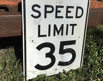 Peut inclure: Panneau de limitation de vitesse en métal blanc avec du texte noir. Le panneau indique "SPEED LIMIT 35".