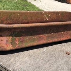 May include: A large, rusty metal planter with a rectangular shape. The planter has a weathered, aged appearance with a green patina.