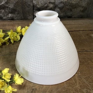 May include: White glass lampshade with a textured, waffle-like pattern. The shade is cone-shaped and has a white, opaque finish.