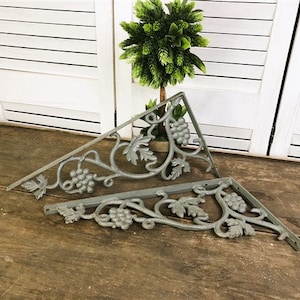 Peut inclure: Deux supports d'étagère en métal gris avec un motif de vigne. Les supports sont en forme de triangle et présentent un motif décoratif de volutes.