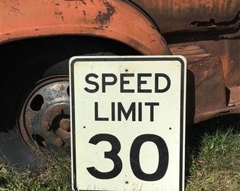 Peut inclure: Un panneau de limitation de vitesse blanc et noir avec le texte "SPEED LIMIT 30" sur un camion rouillé.
