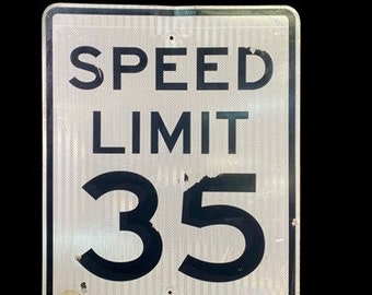 Peut inclure: Un panneau de limitation de vitesse en métal blanc avec du texte noir. Le panneau indique "SPEED LIMIT 35".