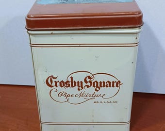 May include: A white metal tin with a brown lid and a brown label that reads "Crosby Square Pipe Mixture REG. U.S. PAT. OFF."