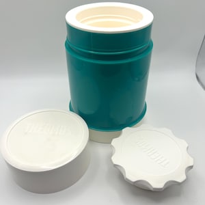 May include: A teal and white Thermos food jar with two white lids. The jar is cylindrical with a white interior and a teal exterior. One lid is a flat disc with the word "THERMOS" embossed on it. The other lid is a white, round container.