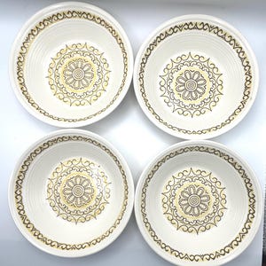 May include: Four white ceramic bowls with a brown and yellow floral design in the center and around the rim. The bowls have a textured surface and are arranged in a square formation.