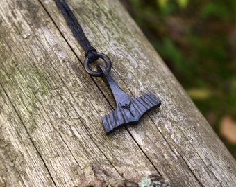 Colgante pequeño con martillo de Thor de hierro negro forjado, disponible con runas vikingas personalizadas. Se vende con piel de reno o hilo de algodón negro.