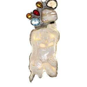Puede incluir: Un collar de cadena de plata con un colgante que presenta una calavera blanca tallada en una concha. La calavera está adornada con piedras preciosas de colores, incluyendo azul, rojo, amarillo y naranja.