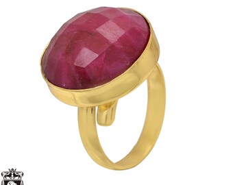 Könnte beinhalten: Ein goldener Ring mit einem großen, facettierten, roten Edelstein. Der Ring ist in einer schlichten, goldenen Fassung gefasst.