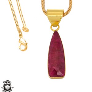 May include: A gold chain necklace with a teardrop-shaped pendant featuring a large, deep red gemstone.