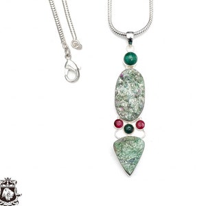 Może przedstawiać: Srebrny łańcuszek z naszyjnikiem, na którym znajduje się wisiorek z owalnym kamieniem w kolorze zielonym i białym, dwoma mniejszymi kamieniami zielonymi i trzema czerwonymi kamieniami.