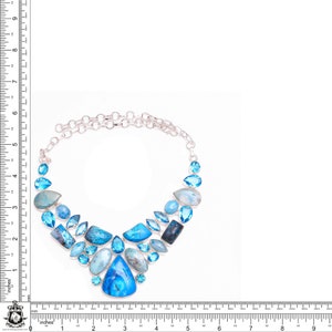 Puede incluir: Un collar de plata con un dise&ntilde;o en forma de V adornado con una variedad de piedras preciosas azules, incluyendo aguamarina, topacio y turquesa.