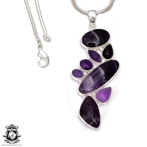 Pode incluir: Um colar com pingente de prata com um conjunto de pedras preciosas polidas em tons de roxo e preto. O pingente tem um design abstrato com pedras ovais e em forma de gota. O colar tem uma delicada corrente de prata.