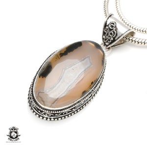 May include: A silver pendant featuring an oval agate stone. The stone has a white and brown pattern. The pendant is on a silver chain.