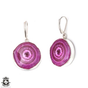 Puede incluir: Un par de pendientes de plata con detalles de piedra de ágata rosa. Los pendientes tienen un diseño redondo y circular con un patrón de espiral rosa y blanco.