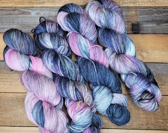 Könnte beinhalten: Fünf Knäuel Garn in Blautönen, Lila und Rosa. Das Garn ist handgefärbt und hat ein buntes Farbmuster.