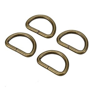 May include: Four gold-toned metal D-rings. The rings are all the same size and shape.
