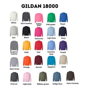 May include: A color chart of Gildan 18000 sweatshirts in various colors, including white, black, red, and blue. The text "GILDAN 18000" is at the top. Each sweatshirt is displayed individually, showcasing the available color options for apparel.