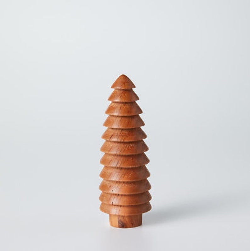 May include: A wooden Christmas tree ornament with a brown finish. The tree is made of stacked, rounded pieces of wood.