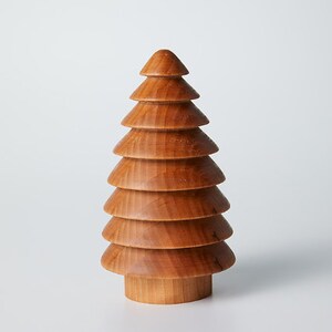 May include: A wooden Christmas tree ornament with a brown finish. The tree is made of stacked, rounded pieces of wood.