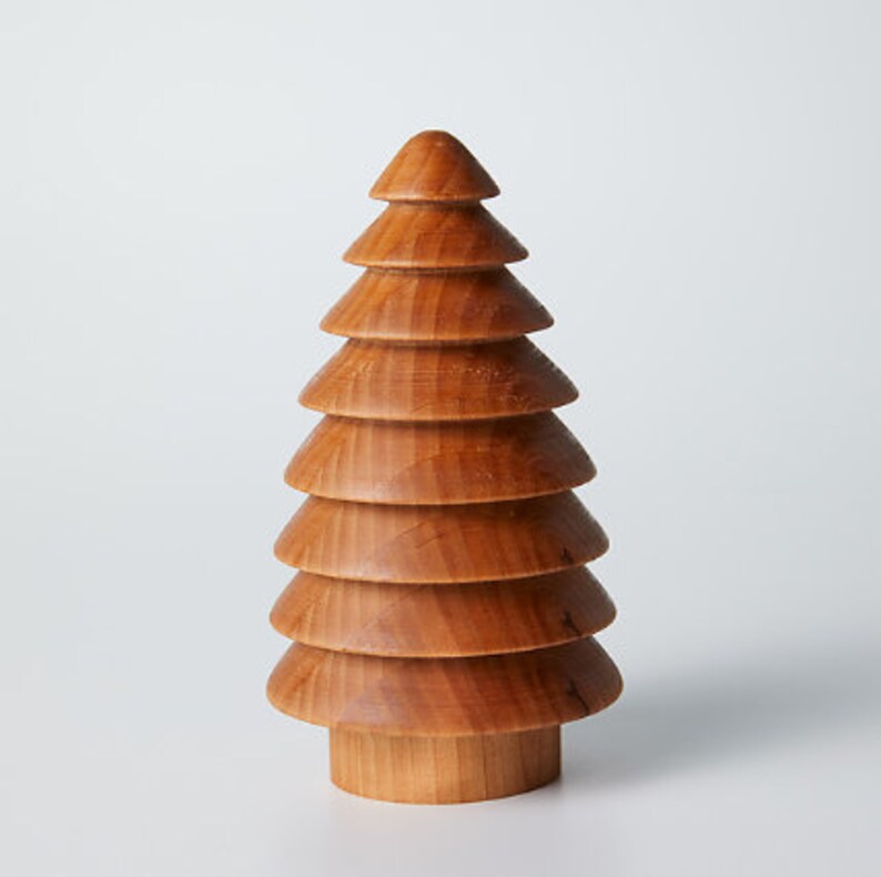 May include: A wooden Christmas tree ornament with a brown finish. The tree is made of stacked, rounded pieces of wood.