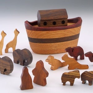 May include: Wooden toy ark with a brown roof and a red trim, surrounded by wooden animal figurines, including giraffes, elephants, and lions.