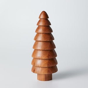 May include: A wooden Christmas tree ornament with a brown finish. The tree is made of stacked, rounded pieces of wood.