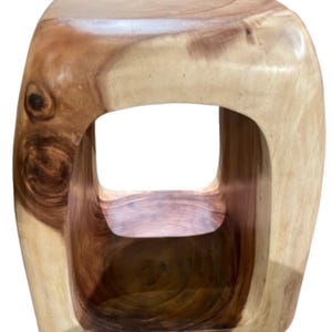 May include: A solid wooden stool with a square opening in the center. The stool is made of light and dark brown wood, with visible grain patterns. The design is modern and minimalist, suitable for various interior styles.
