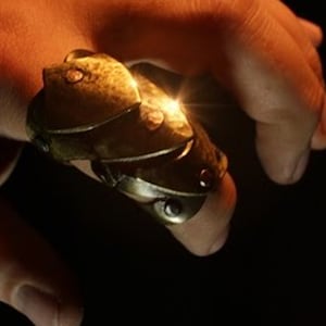 May include: A gold-toned ring with a textured, segmented design. The ring is worn on a finger and has a slight shine.