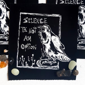 Peut inclure: Patch thermocollant noir et blanc avec un corbeau et le texte "Silence n'est pas une option".