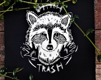 May include: Black and white embroidered patch featuring a raccoon with the text "Raccoon Trash" underneath.