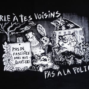 May include: A black fabric item featuring a white screen-printed graphic with the text PARLE À TES VOISINS, PAS DE FASCISTES DANS NOS QUARTIERS, and PAS À LA POLICE, depicting a cat, a dog, a bird, and a tree in a hand-drawn style.