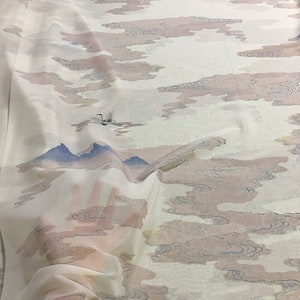 Puede incluir: Tela blanca transparente con un diseño de acuarela de nubes rosas y grises, montañas azules y grullas. La tela tiene una apariencia delicada y fluida, lo que sugiere que es ligera y adecuada para cortinas o ropa.