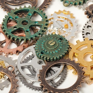 Może przedstawiać: Kolekcja różnych kół zębatych w stylu steampunk w odcieniach brązu, miedzi, srebra i złota. Koła zębate różnią się rozmiarem i wzorem, niektóre wykazują oznaki utlenienia i zużycia, tworząc estetykę vintage. Idealne do projektów rzemieślniczych i przemysłowych.